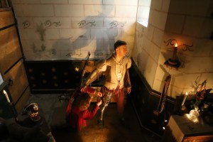 A soldier getting some help from a servant to put his armor on